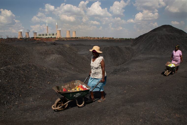 Women push wheelbarrows atop a coal mine dump at the coal-powered Duvha power station, near Emalahleni east of Johannesburg, in 2022.
