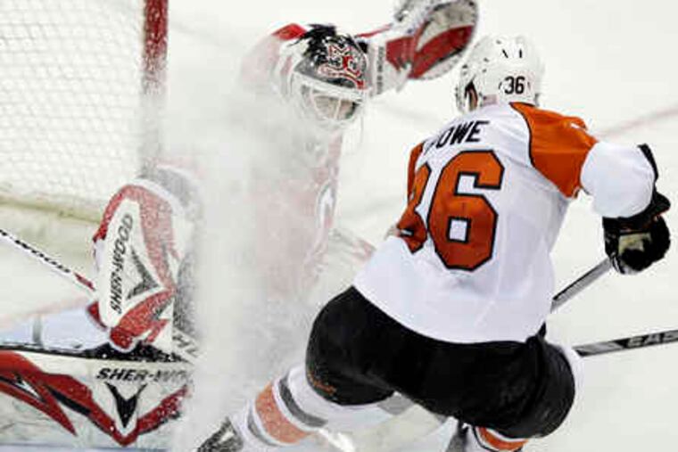 The Flyers' Darroll Powe gives Devils goalie Martin Brodeur a face full of ice.