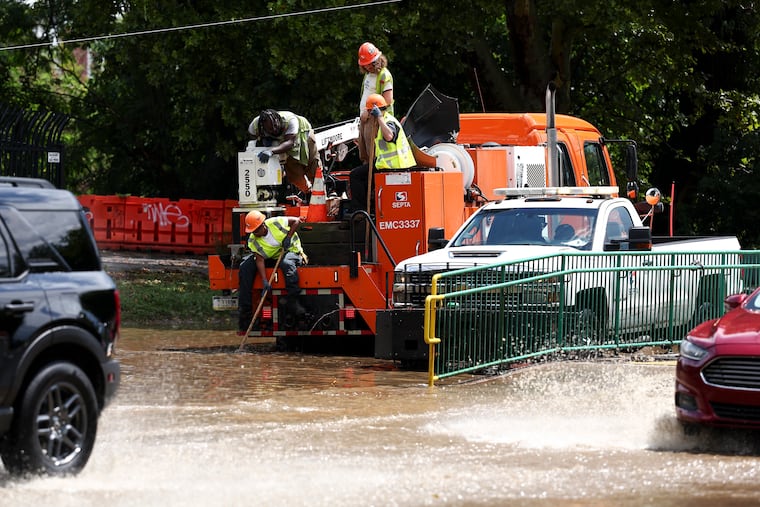 SEPTA workers clear a drain at the flooded intersection of 33rd Street and Girard Avenue on Monday, July 6, 2026, in Philadelphia, Pa.