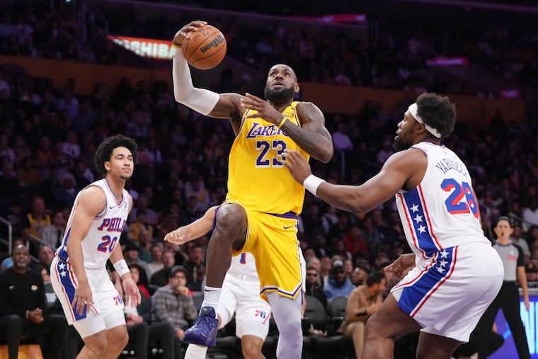 Los Angeles Lakers star LeBron James (center) drives past Sixers guard Jared McCain (left) and forward Guerschon Yabusele on Friday night.