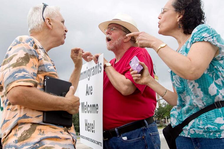 Immigration supporters David Smith, center, and Rona Smith debate with an anti-immigration protester on Saturday, Aug. 2, 2014, in Conroe, Texas. Texas Gov. Rick Perry plans to use $38 million in emergency funds to begin the deployment of up to 1,000 National Guard troops along Texas' border with Mexico, his office said. Perry intends to use the Guardsmen to help law enforcement as a surge of people from Central America, including thousands of children, crosses into the United States. (AP Photo/Conroe Courier, Jason Fochtman)