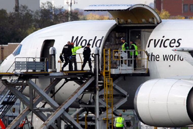 Investigators board a United Parcel Service jet isolated on a runway at Philadelphia International Airport on Friday. Law enforcement officials are also investigating reports of suspicious packages on a cargo plane in Newark. (AP Photo / Matt Rourke)