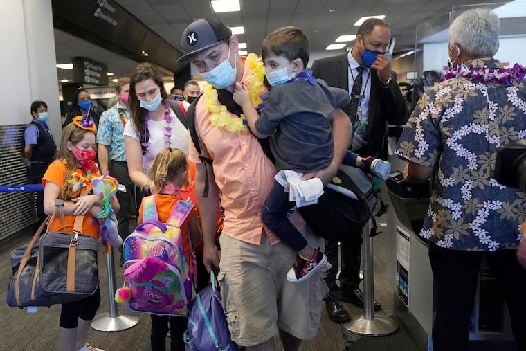 In this Oct. 15, 2020 file photo, Hawaii resident Ryan Sidlow carries his son Maxwell as their family boards a United Airlines flight to Hawaii at San Francisco International Airport in San Francisco.