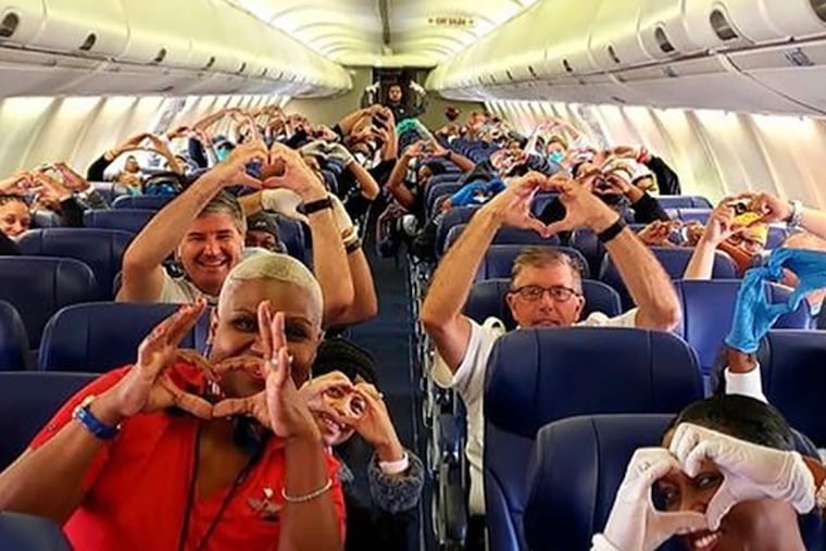 This Friday, March 27, 2020, photo provided by Southwest Airlines employee Dayartra Etheridge shows health care workers, other passengers and flight crew aboard a Southwest flight from Atlanta to New York's LaGuardia Airport holding their hands in the shape of a heart, before the plane pushed back from the gate, at Hartsfield-Jackson Atlanta International Airport. The airline had not been selling the middle seats due to COVID, but will sell all the seats on its planes for travel starting Dec. 1. (Dayartra Etheridge via AP)