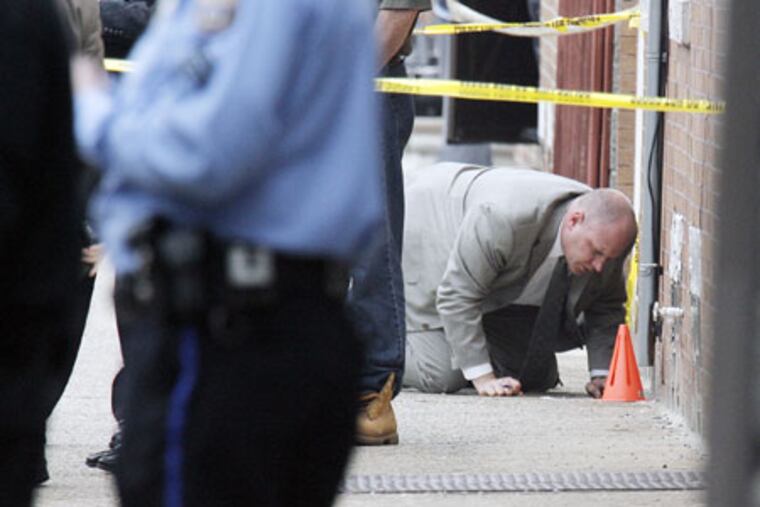 A police officer looks for evidence at the corner of Almond and Schiller Streets in Port Richmond, where Sgt. Stephen Liczbinski was shot.