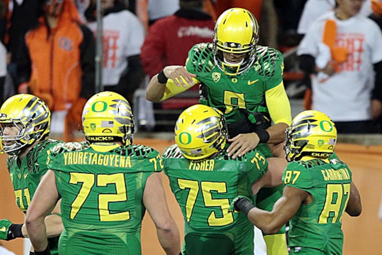 Oregon quarterback Marcus Mariota is congratulated by teammates after a touchdown. (Scott Olmos/USA Today Sports)