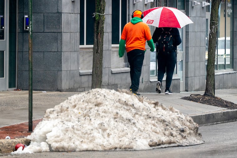 Pedestrians walk past a polie of winter remnants last month in North Philadelphia. The region may get a winter reminder Thursday afternoon.