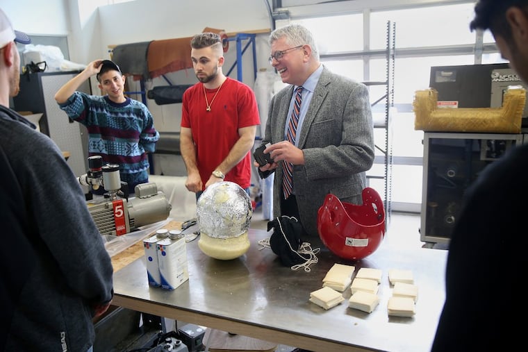 Stanton Miller, right, a surgeon and executive director of the Jefferson Center for Injury Research and Prevention, works with engineering students, including Olivia Mermigos, left, and Andrew Gabriele, about their helmet design project on the East Falls campus. TIM TAI / Staff Photographer