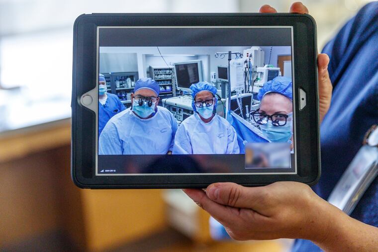 Cardiac surgeon Mauricio Garrido, left, and other members of a surgery team at Abington hospital, use telehealth to communicate more quickly with family members eager to know what's happening in the O.R. MICHAEL BRYANT / Staff Photographer