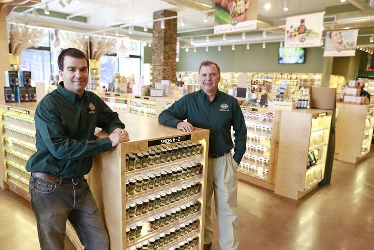 William Betz III (left) and William Betz Jr. in the reopened Penn Herb Co. The new building at Second and Green Streets features information kiosks, grocery items and 14 apartments. ( DAVID SWANSON/Staff Photographer)