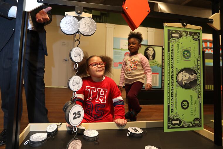 Milan Brintley, 4 (center), and Ariyel Smith, 4, learn how many coins make up a dollar in the Please Touch Museum's new exhibition, Cents & Sensibility.