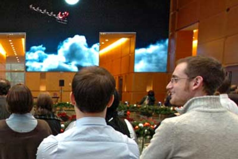 In a scene from the video, Santa and his reindeer fly across the night sky as employees watch. ( Clem Murray / Staff Photographer )