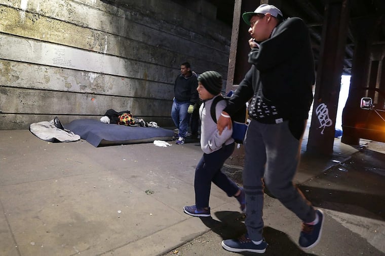 Pedestrians navigated around workers clearing out the homeless sleeping under the bridge at Kensington and Lehigh in October.
