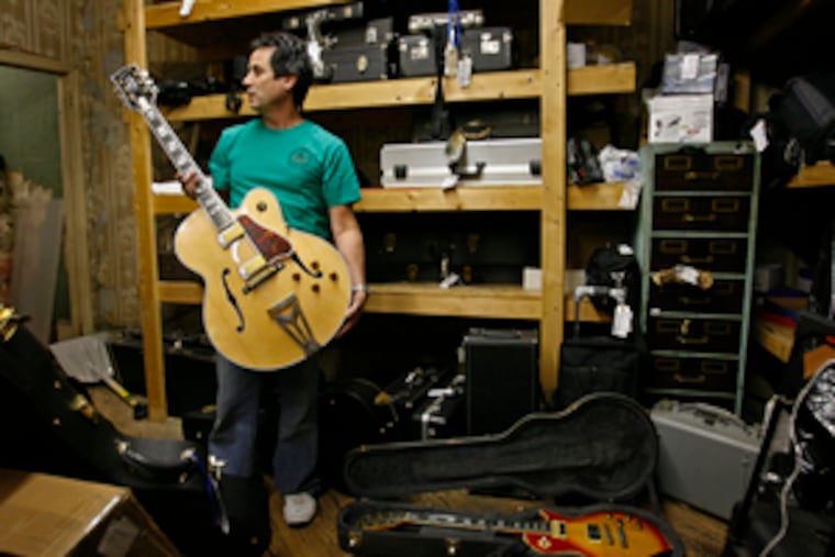 Business at his Society Hill Loan is up about 20 percent over last year, Nat Leonard says. He is holding one of many guitars there; among them, he says, are 30 pawned by a Grammy-winning musician hurt by the real estate slump.
