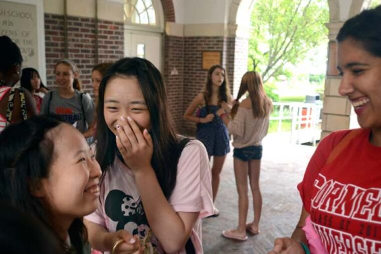 Haddonfield Memorial High School graduate Katie Kurtz (right), 17, who will be spending this gap year studying at Sofia University in Tokyo before going to Cornell University, talks with Kana Hakuta (center), 16, and Kanako Hashimota (left), 17, from Saitama Prefectural Kasukaba Girls' High School in Japan as they wait at the high school to board a bus to go tubing on the Delaware River August 1, 2013. Kurtz's family is hosting a student, along with other families in the Haddonfield Japan Exchange progam run by octogenarian Bill Brown as a labor of love. ( TOM GRALISH / Staff Photographer )