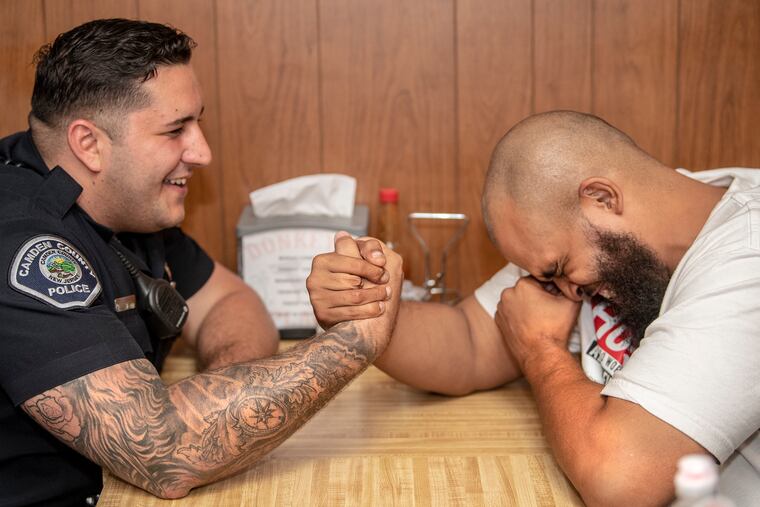 Camden County police officer Andrew Smith (left) interacts with former drug dealer, Hassan Atkins, at Donkeys restaurant in Camden on Thursday, Oct. 3, 2019. Smith rushed Atkins to a hospital, saving his life, after Atkins was wounded in a gun fight.