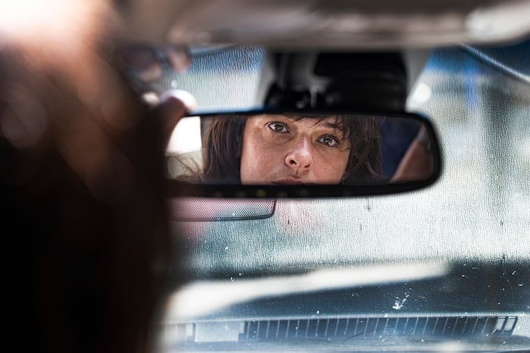 Stephanie Vincent, an activist with Montgomery County Community Watch, is seen in the rearview mirror of her car on Wednesday in Norristown — in the same vehicle she and her team often use to patrol the streets. As part of Montgomery County’s growing rapid-response team, she helps track ICE activity, document enforcement actions, mobilize protesters, and encourage resistance to enforcement in the community.