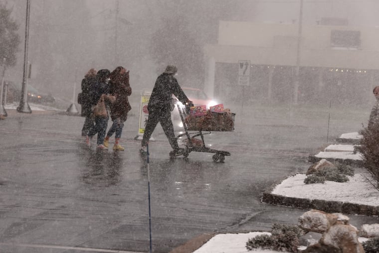 Shoppers at Wegman’s in Cherry Hill scurry in and out of the store during an intense snow squall on Monday. Several hit the region; one in Schuylkill County was deadly.