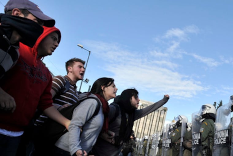 Greek protesters shout slogans in the faces of police guarding the parliament buildingin Athens. Demonstrators in France, Germany and Turkey put on shows of support.
