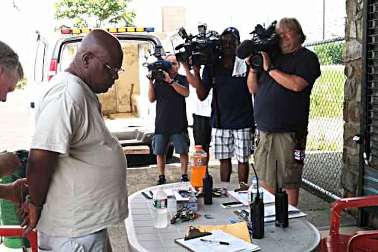 Police prepare to put away a man after he got arrested for allegedly patronizing a prostitute in Kensington. He was the first nabbed in a sting targeting johns. The goal was to shame the men (hence the TV cameras) to discourage them or others from seeking sex on the streets. (Dana DiFilippo / Staff)