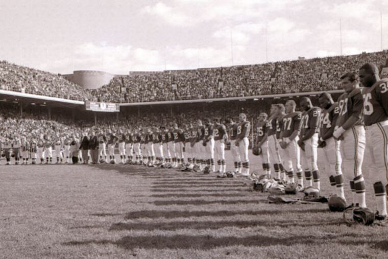 The Eagles stand for a moment of silence before the start of their game against the Washington Redskins at Franklin Field on November 24, 1963, two days after the assassination of President John F. Kennedy. NFL Commissioner Pete Rozelle decided that NFL games should be played that day. (Alexander Deans/Staff file photo)