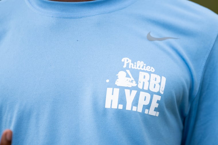 A member of the North Heritage Baseball League wears a shirt detailing the league that the Phillies help run at Hunting Park in Philadelphia.