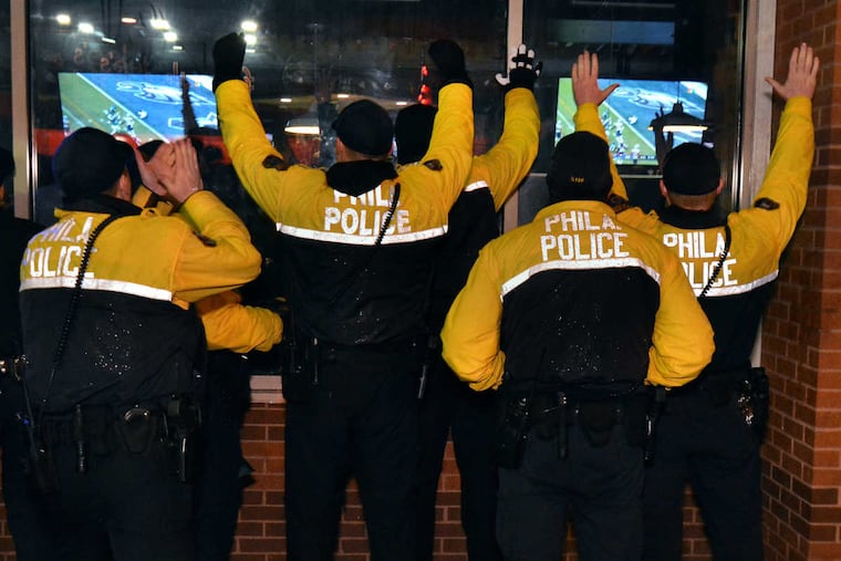 A group of Philadelphia Police Officers watch the Eagles take on the New England Patriots in Super Bowl LII outside of The Draught Horse Pub & Grill near Temple University's campus during on Feb. 4, 2018.