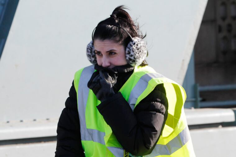 Volunteer Nina Casella braves the cold and wind on the Ben Franklin Bridge while waiting for runners during the Cooper-Norcross "Run The Bridge" race. (MICHAEL S. WIRTZ/Staff Photographer)