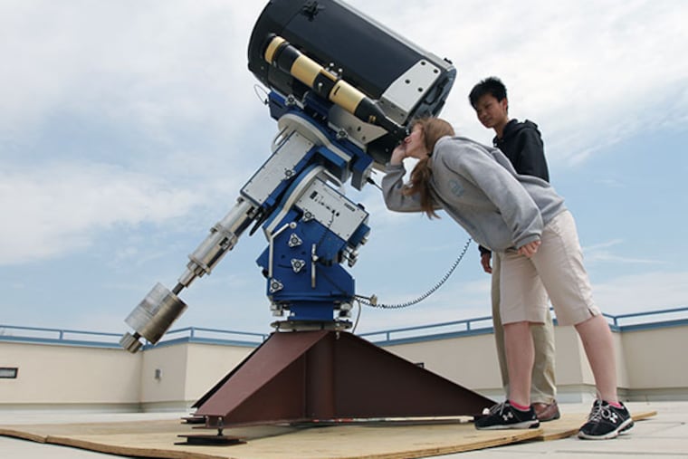 Cecily Sanders, 11th grade, demonstrates the telescope with Anthony Chu, 10th grade, on the roof of the MaST Charter School in Northeast Philadelphia on April 22, 2014. ( DAVID MAIALETTI / Staff Photographer )