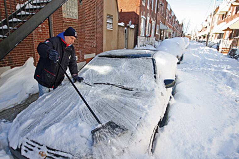 Sam Costilano, of the 1100 block of Daly Street in South Philadelphia,
uses a broom to clear snow from his car Sunday morning. The street had not been plowed and had snow drifts of more than 3 feet.
(Michael Bryant / Staff Photographer)