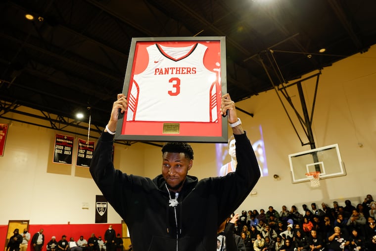 Justin Edwards holds his retired Imhotep boys’ basketball team jersey during a halftime ceremony at Imhotep Institute Charter High School in North Philadelphia on Thursday.