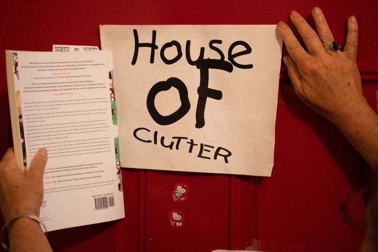 A woman shows off a sign taped to her front door reading in East Kensington.