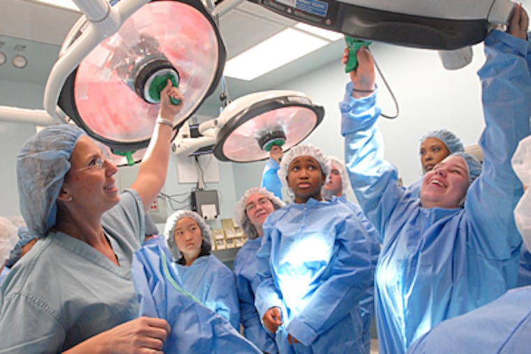 At Deborah Heart and Lung Center, charge nurse Lisa Guarini, left, shows high school students how to adjust lights in the operating room. (April Saul / Inquirer