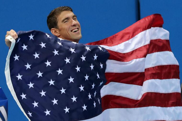 Michael Phelps walks with the U.S. flag Sunday during the medal ceremony for the men's 4 x 100-meter medley relay final..