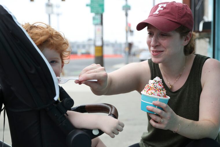 Rachel Weinick feeds her son, Calvin, 2, some peaches ricotta/mascarpone soft-serve ice cream topped with jimmies from Porco's Porchetteria & Small Oven Pastry Shop in Philly's Point Breeze neighborhood last month.