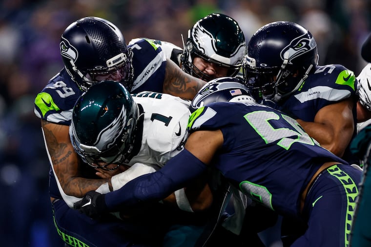 Eagles quarterback Jalen Hurts gets stopped by Seattle Seahawks defensive end Leonard Williams, left, and linebacker Bobby Wagner, right, on the third down in the second quarter of the game against the Seattle Seahawks at Lumen Field in Seattle, Wash. on Monday, Dec. 18, 2023.
