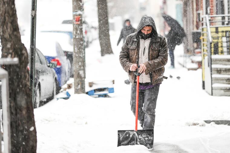 Amer Shammakh shovels the sidewalk outside of his small grocery store on Girard Avenue in Fishtown in 2021.