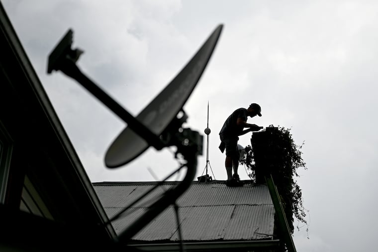 A technician installs equipment to bring broadband internet to a home in central Pennsylvania's Mifflin County. Biden’s infrastructure bill could expand rural broadband.(The satellite dish is inoperable, and belonged to a previous resident.)
