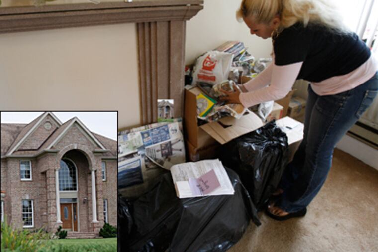 Isabel Santos packs belongings at her Kensington home in anticipation of possible eviction. Pictured at left is the home of Robert N. Coyle Sr., a real-estate mogul, accused by tenants of misleading them. (David Maialetti / Staff)