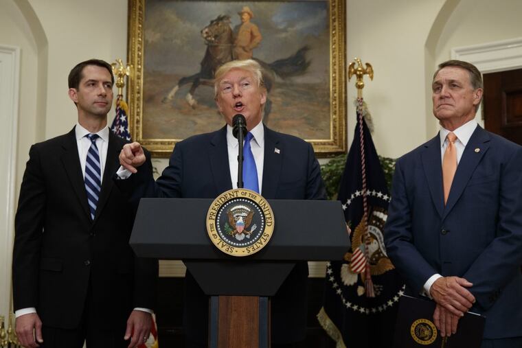 Sens. Tom Cotton (left) and David Perdue look on as President Trump speaks during the unveiling of the RAISE Act.