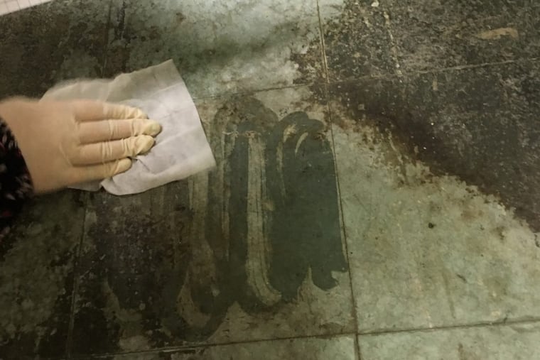 A staffer uses a “Ghost Wipe” to test for lead residue on a hallway floor at J. Hampton Moore Elementary School.