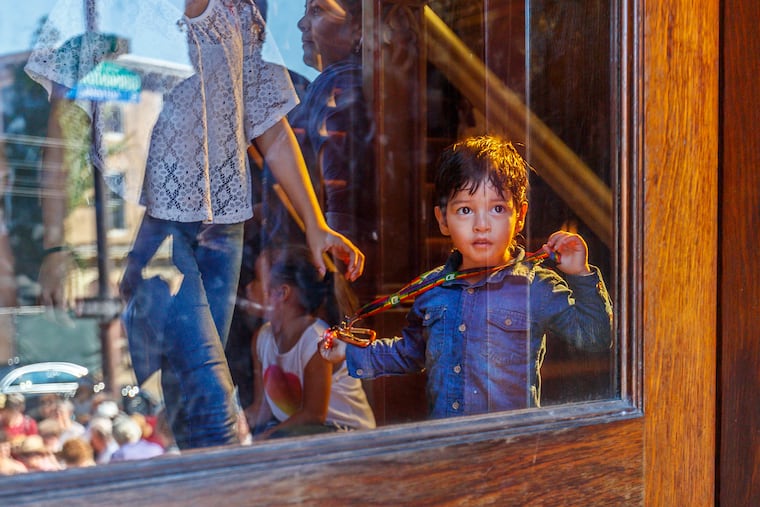 Yamie Reyes, 7, looks out the front door from the inside of the First United Methodist Church of Germantown, seeing the crowd that gathered outside to welcome him, his family and the Thompson family from Jamaica.