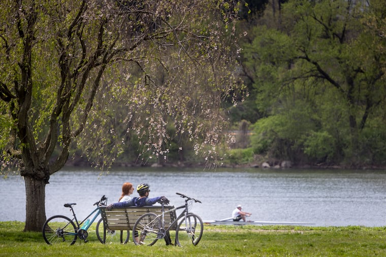 A couple of people enjoy a warm afternoon on a bench along Kelly Drive at Fountain Green on Tuesday, April 26, 2022.