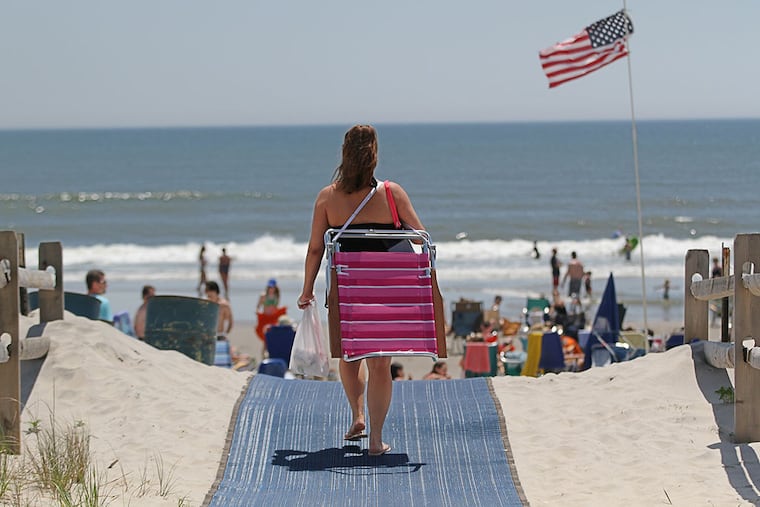 Armed with a beach chair, a woman walks up the path from 39th Street toward the beach at Sea Isle City. ( Michael Bryant / Staff Photographer )