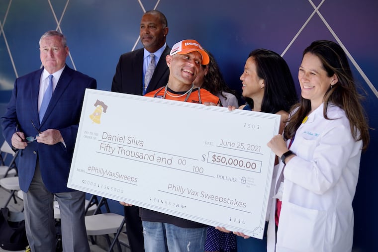 From left, Mayor Jim Kenney, Delaware Valley Community Health CEO A. Scott McNeal, Daniel Silva of Oak Lane, University of Pennsylvania professor Angela Duckworth, and Julia DeJoseph, chief medical officer of Delaware Valley Community Health, pose with a ceremonial check for $50,000 during a news conference announcing Silva as a first-round winner of the Philly Vax Sweepstakes.