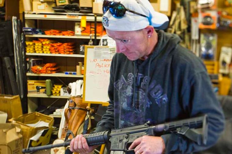 At Delia’s Gun Shop in Northeast Philadelphia, John McCarrapher of Frankford handles an AR-15 rifle. McCarrapher said he was looking to purchase his first handgun.