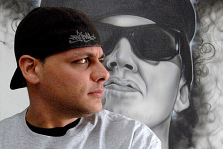 Fred Sicoli with an airbrushed portrait of a customer, BMX biker Rick Thorne, at Killer Kreations in South Philadelphia. (April Saul / Inquirer)