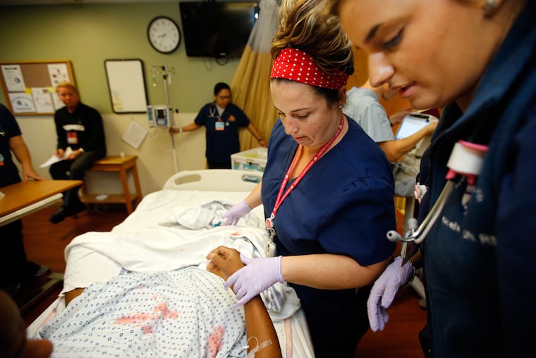 Melissa Ems (center) and Noelle Dominic treat a medical simulation
as the real thing as they tend to an actor showing signs of bleeding
at the Hospital of the University of Pennsylvania.