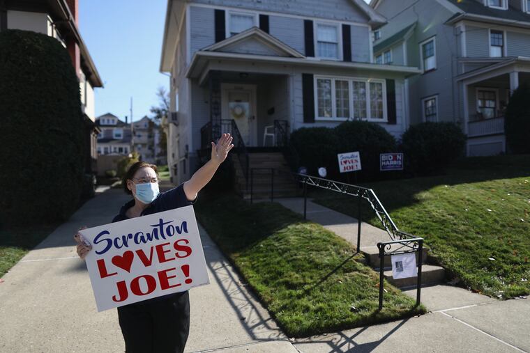 Maureen Hart, who lives up the street, holds a sign in front of Joe Biden’s childhood home in Scranton, Pa., on Saturday, Nov. 7, 2020, after news outlets named Biden as the president-elect. The newly-released 1950 census gives a snapshot of the Biden family’s middle-class lifestyle.
