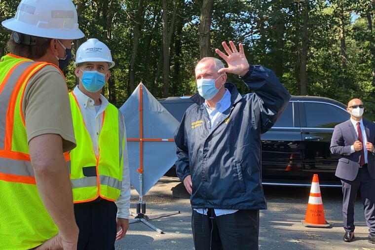 Wearing a mask, New Jersey Gov. Phil Murphy speaks with Jim Fakult, president of Jersey Central Power & Light, in Jackson, Ocean County, on Wednesday in the aftermath of Tropical Storm Isaias.